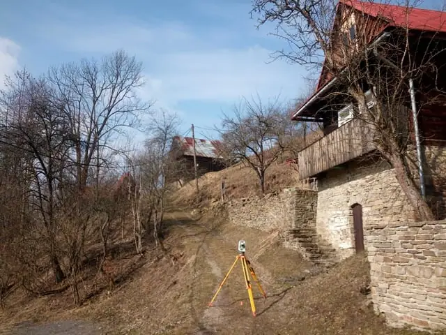 Statív s prístrojom na poľnej ceste pri starom kamennom dome na svahu