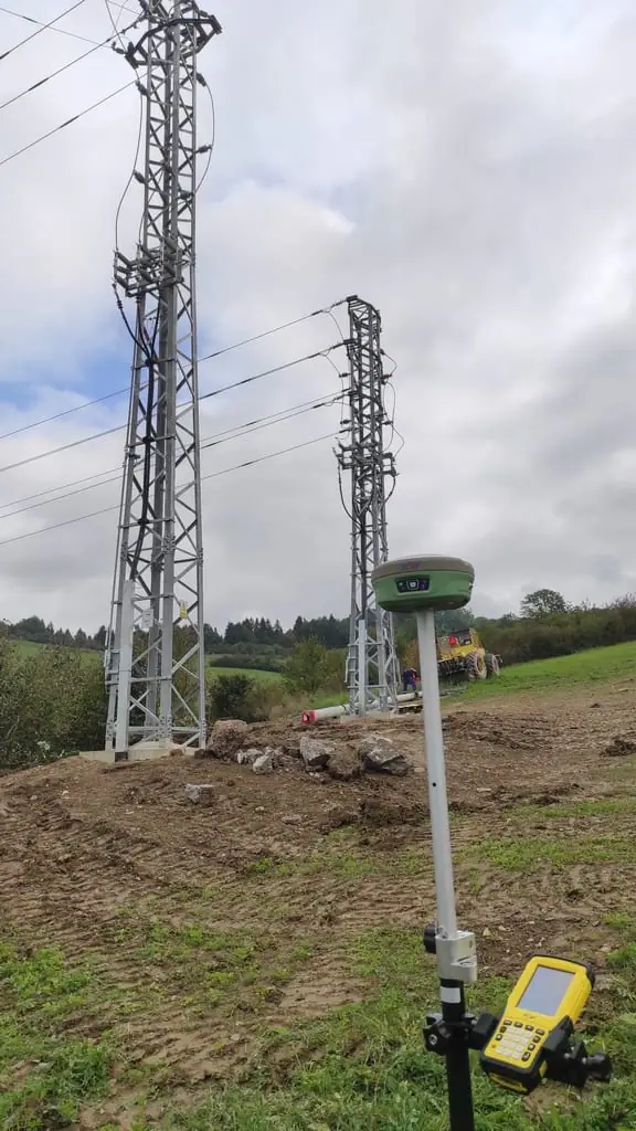 GNSS prijímač na výtyčke na lúke pri stožiaroch elektrického vedenia