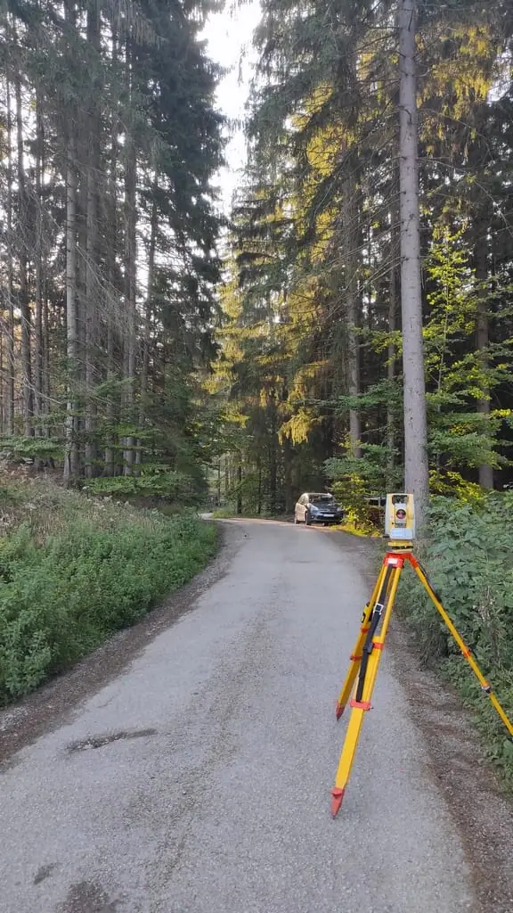 Statív s prístrojom na asfaltovej ceste v lese