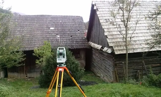 Totálna stanica pred starým dreveným humnom